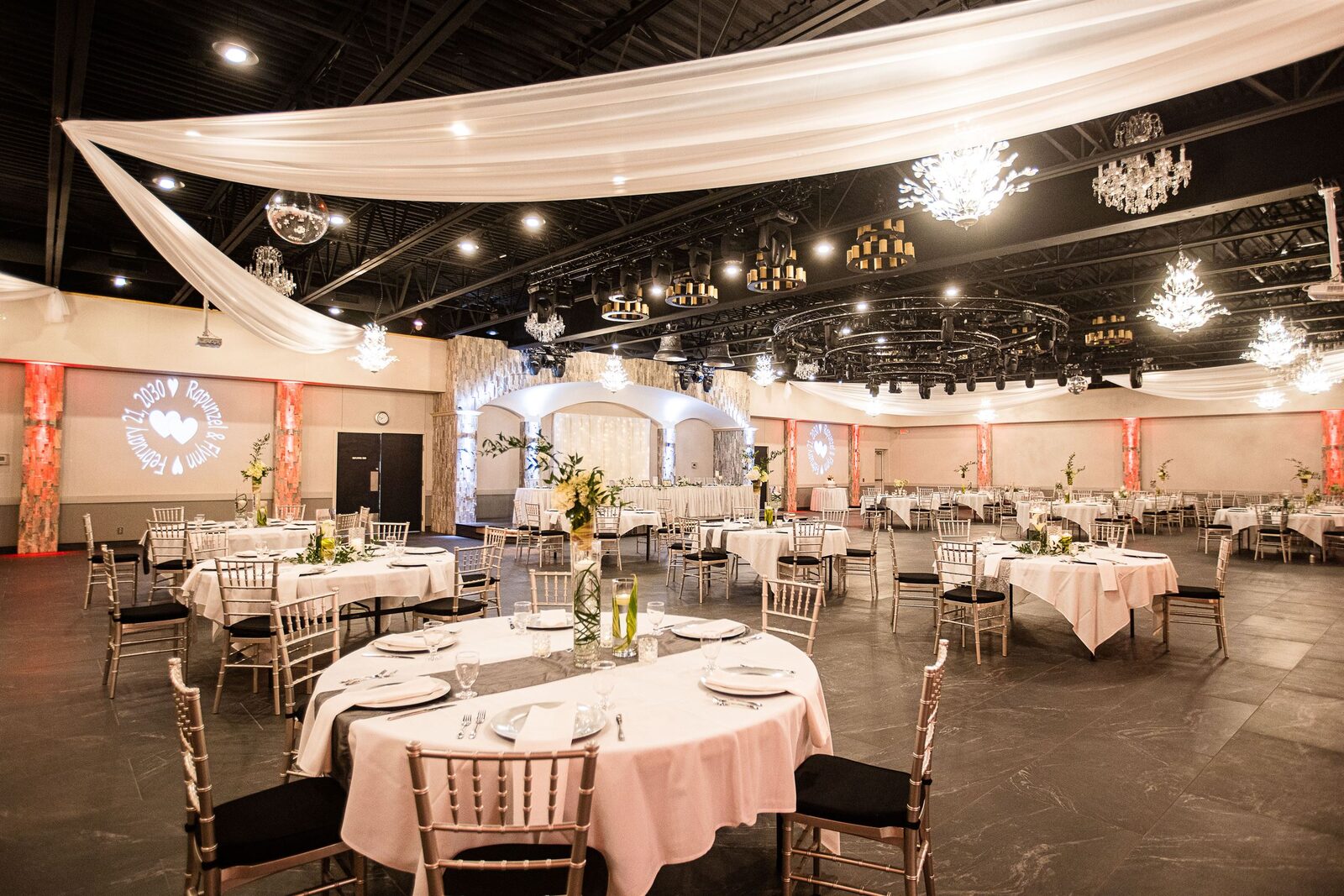 Royal Cliff ballroom in Eagan, MN — wedding reception with chandeliers, flowing white ceiling drapery, gold chiavari chairs and elegant table settings